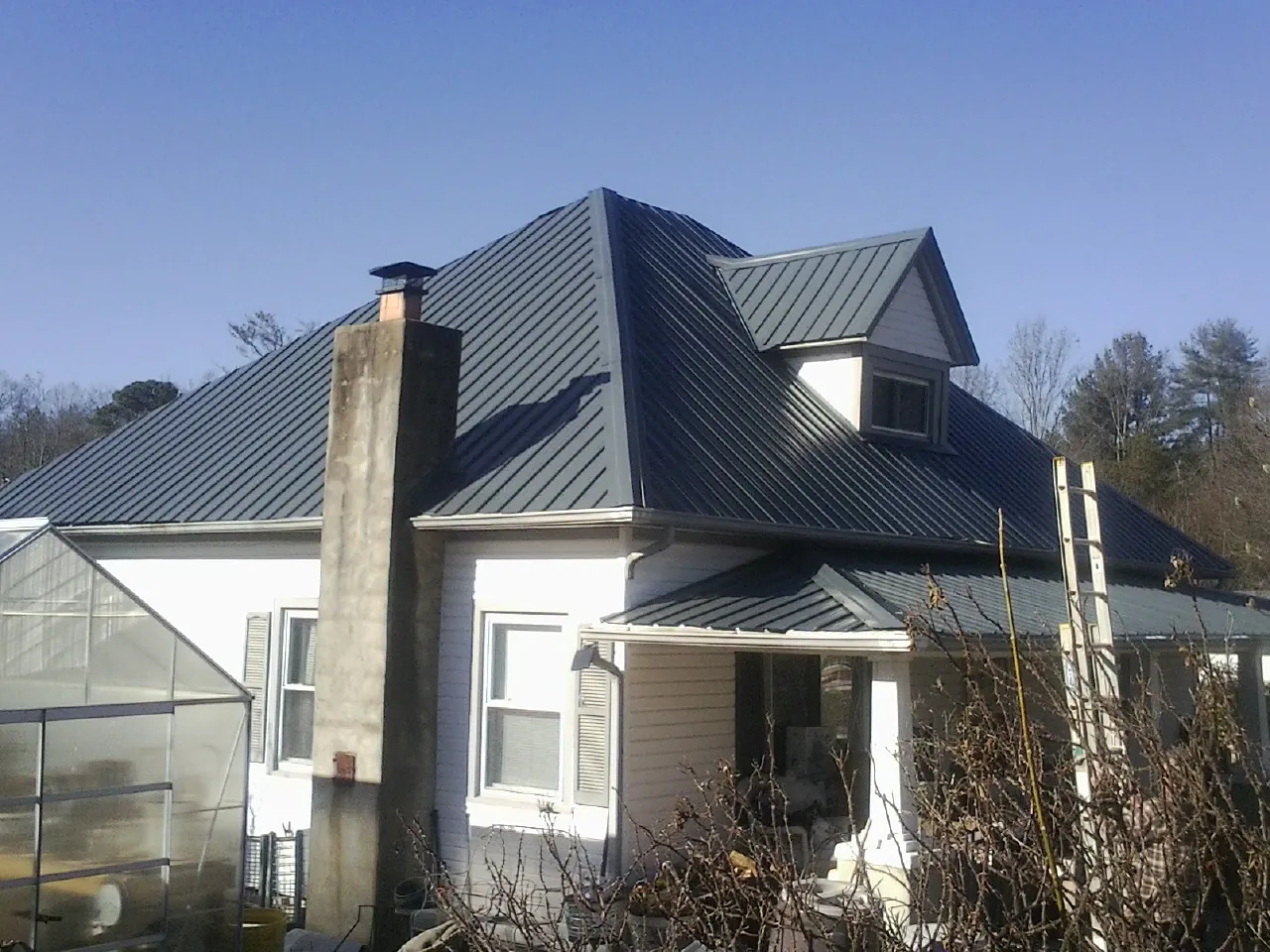 Dark blue standing seam metal roof on a white farmhouse with dormer — Slate & Tile Roof Repair by Roofing Brothers in Thorsby