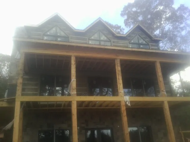 Dormers and porch framing on a large log home under construction — Roof Coating work by our crew in Thorsby