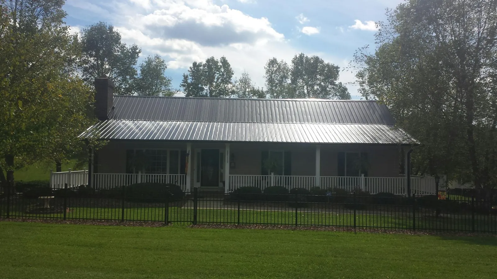 Gray metal roof on a brick ranch with a full width front porch — Gutter Guard Installation work by our crew in Thorsby