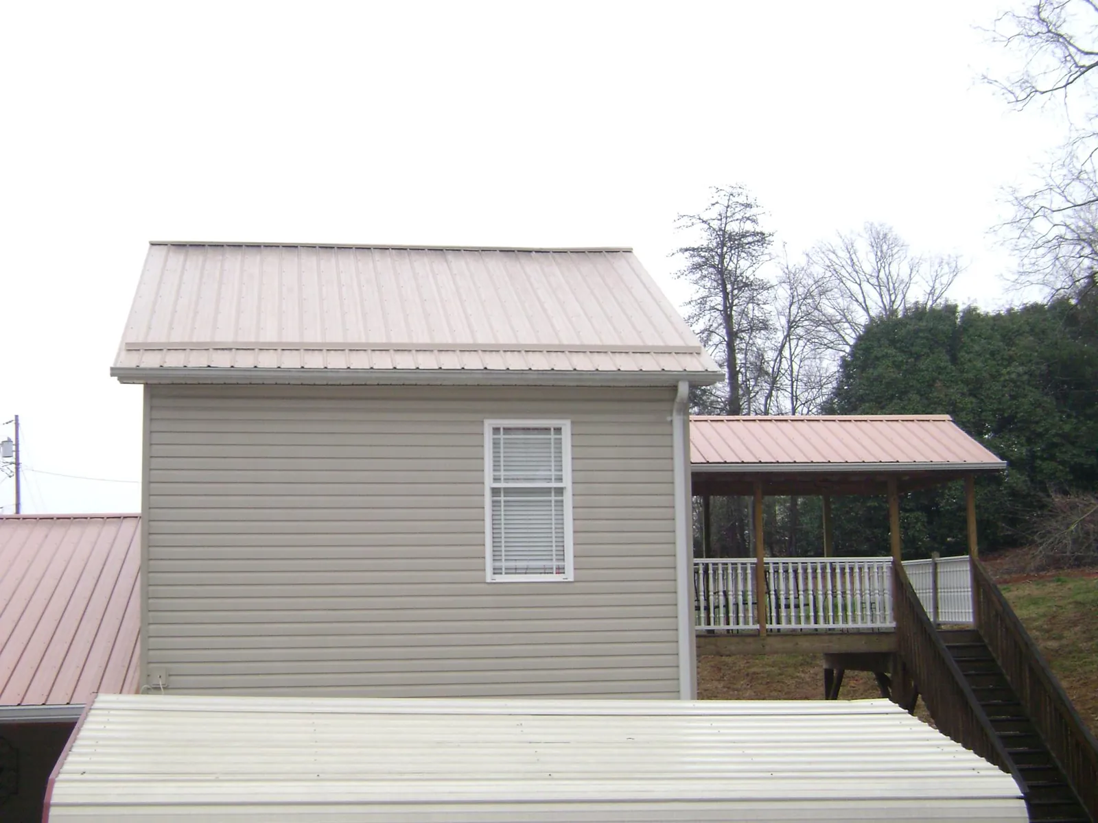 Tan metal roofs on a two story addition and attached porch, from a Roof Replacement job in Thorsby