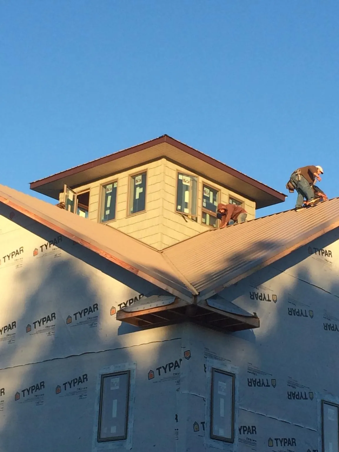 Roofers working around a rooftop cupola on a new metal roof at sunset — Roof Waterproofing in Thorsby by Roofing Brothers